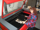 Sophia removing a finished Privacy Shield from the laser cutting machine.