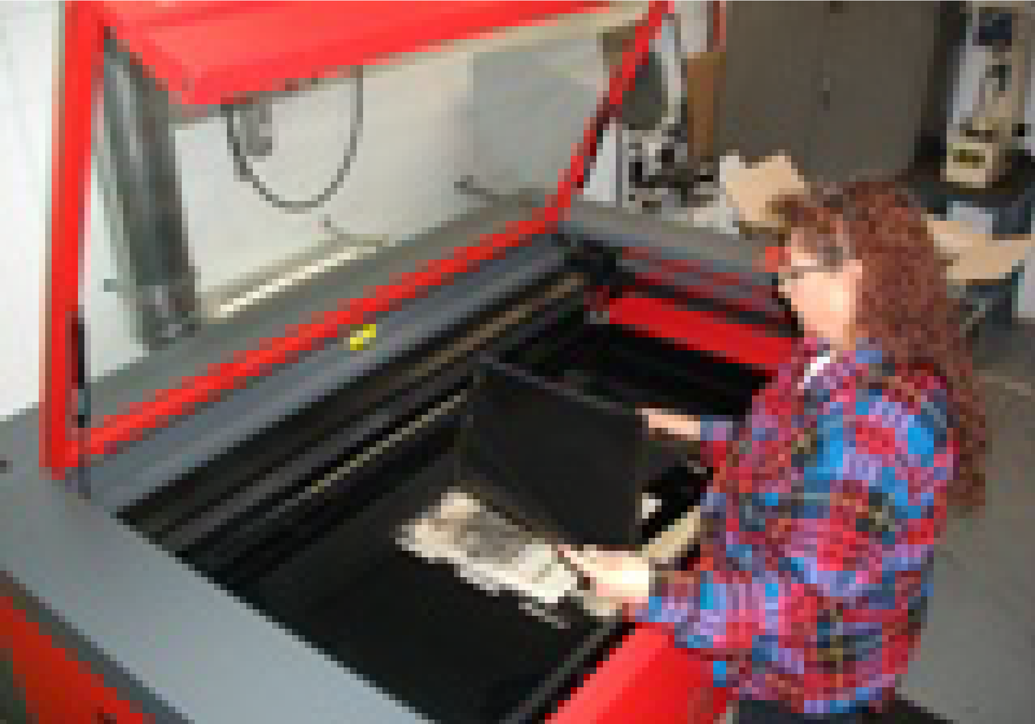 Sophia removing a finished Privacy Shield from the laser cutting machine.