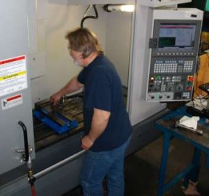 A man is removing a part from a CNC machine