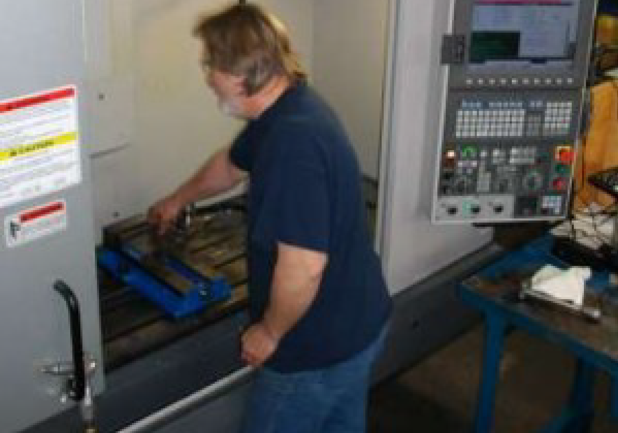 A man is removing a part from a CNC machine