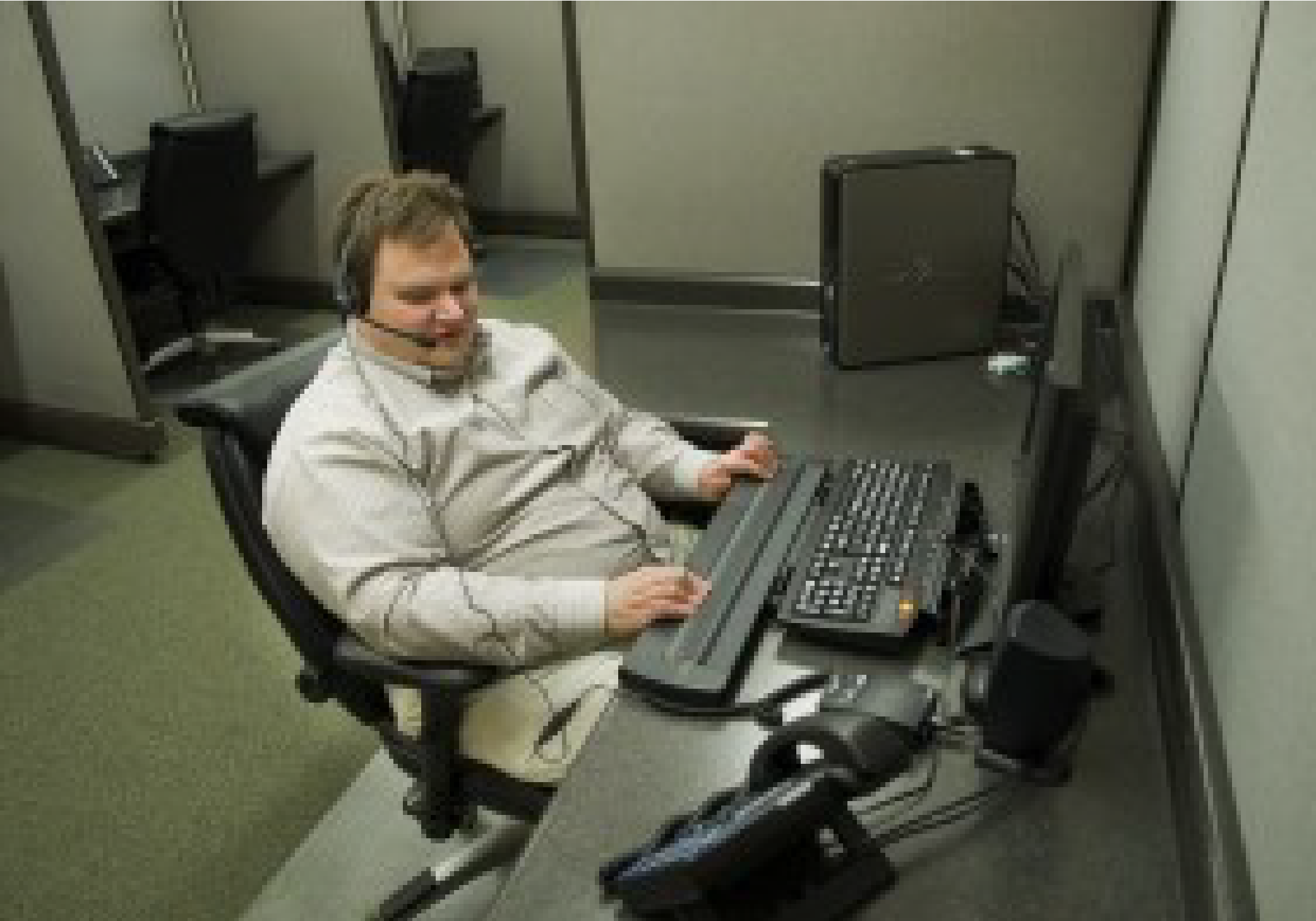Steve sits at a comfortable desk with a computer and braille display on it.