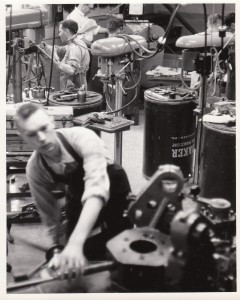 A black and white photo of a man who is blind working in a machine shop.