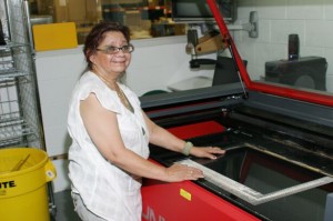 Sophia stands at the privacy filter cutting machine.