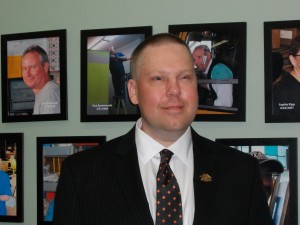 Jim Tess standing in front of our employee wall