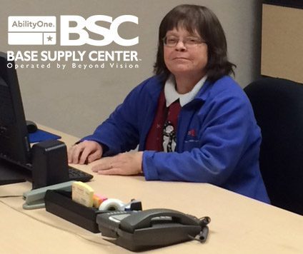 Kris Mize, assistant BSC Manager, sits at a desk. AbilityOne BSC logo.