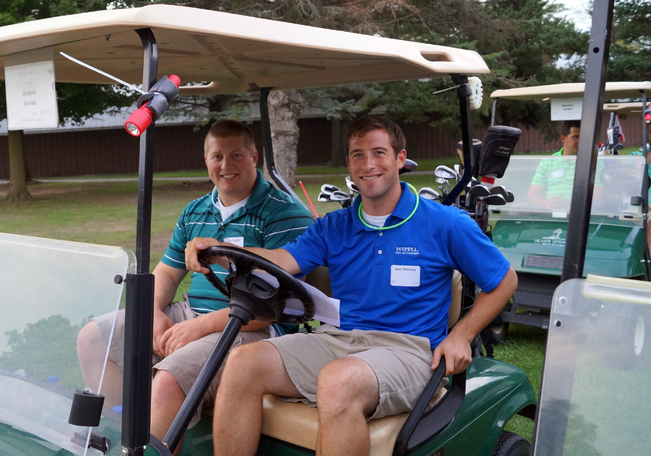 Two young men are very happily sitting in a golf cart.
