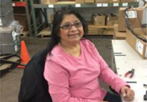 Sophia smiling and wearing a bright pink long sleeve while sitting at her station.