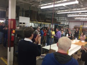Many of the Beyond Vision employees stand around a cake to congratulate Gale Klatt on his retirement.
