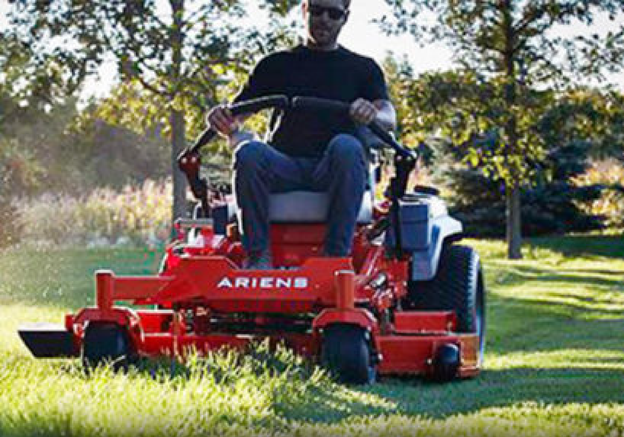 A man is on a large riding lawnmower cutting a lawn