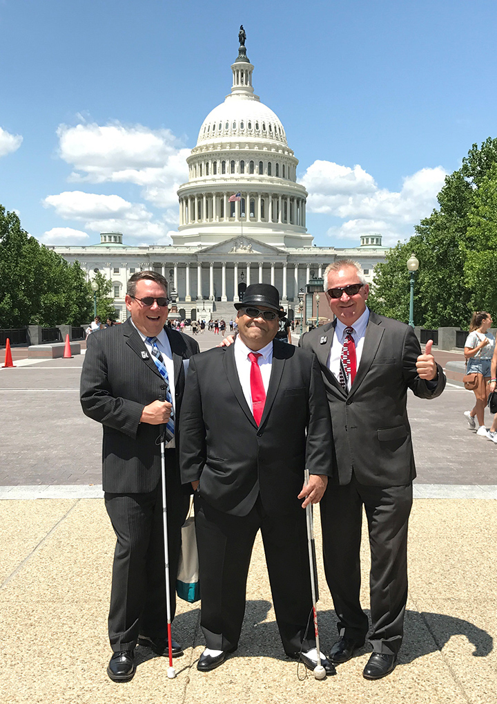 Rob Buettner, Julius Perez and Jim Kerlin stand in front of the Capitol. They are all wearing dark suits and laughing.