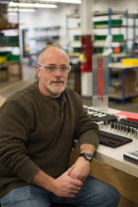 Jim Fritsch sits in front of an assembly desk for SKILCRAFT sockets