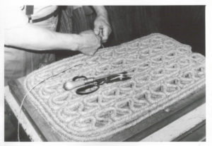 Closeup of a woven rug as a person is finishing off the edges.