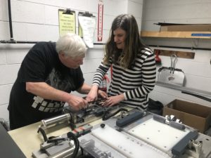Jeff helps Sarah learn how to cut filter material.