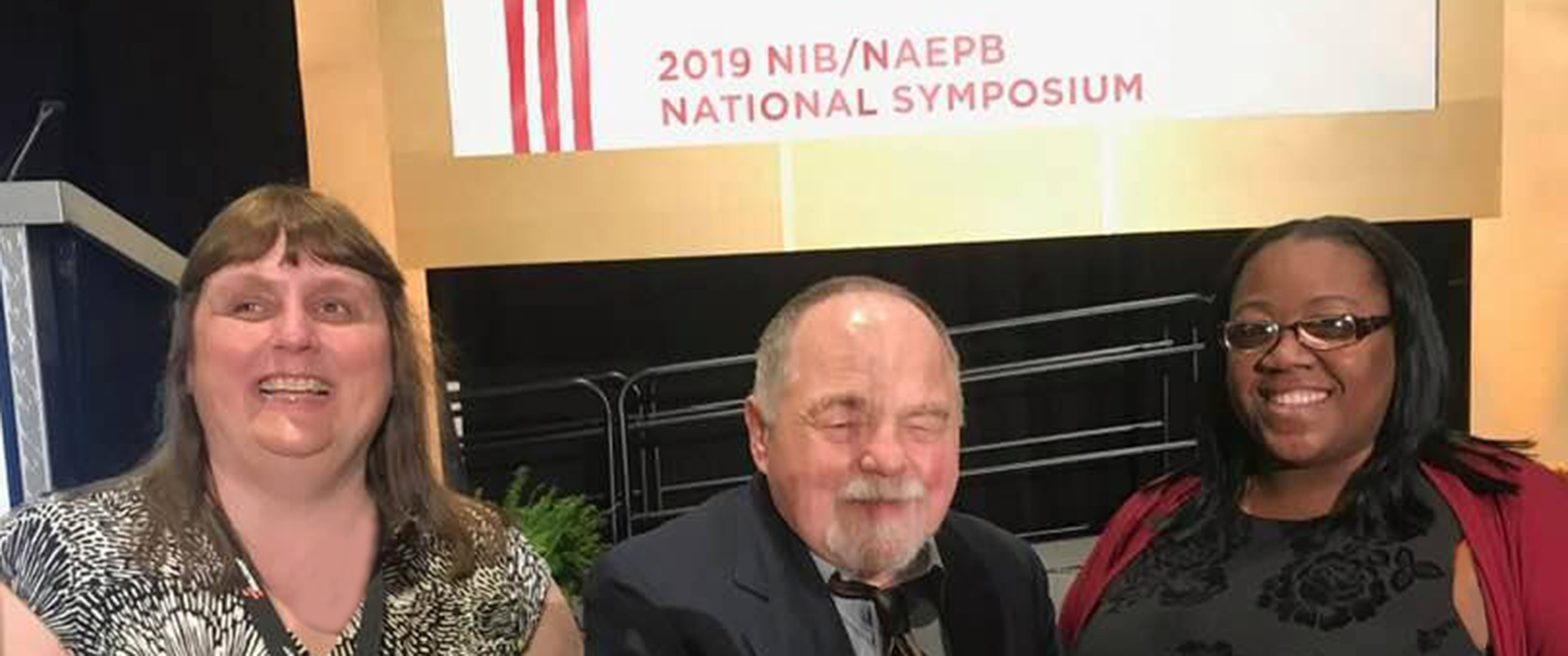 Michelle, Gene and Delonna stand on the stage at the National Conference