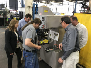 Jed is using the pemming machine as a group of people watch from both sides.