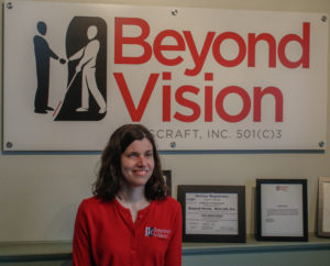 Stacy standind in front of a Beyond Vision sign.