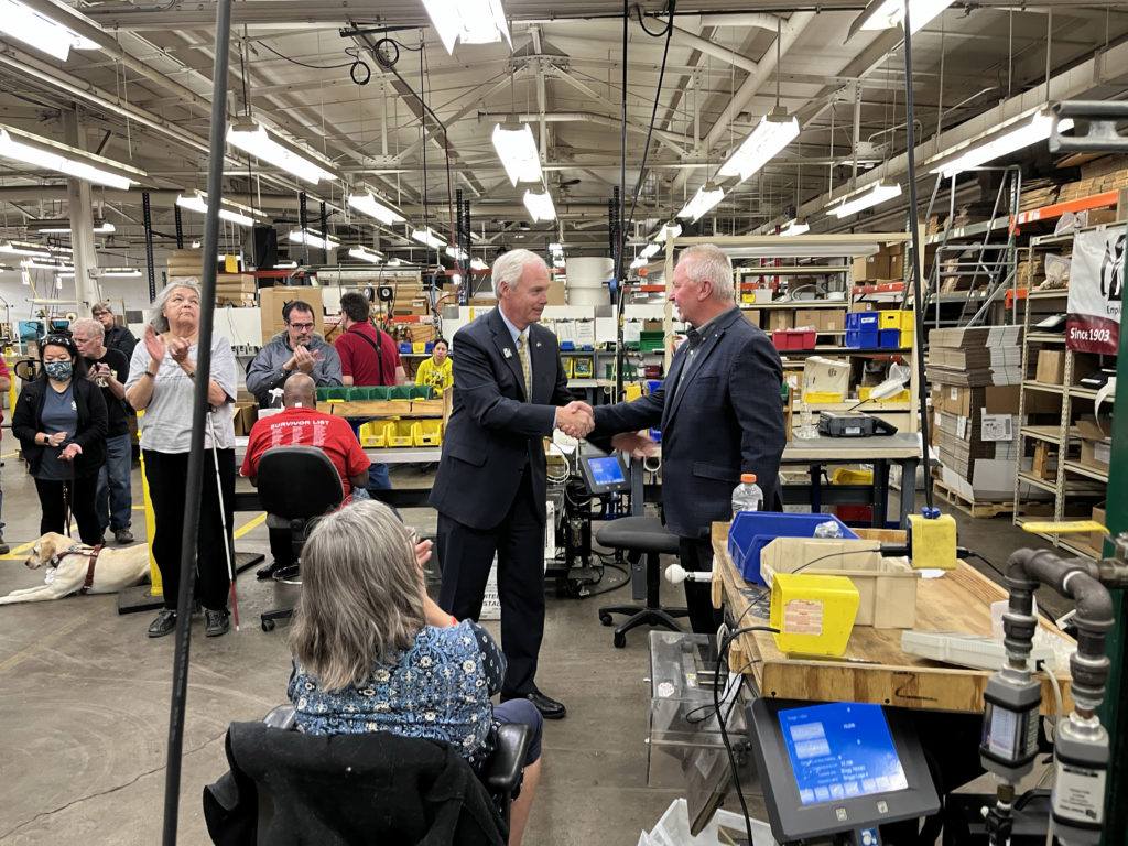 In the assembly and packaging area of Beyond Vision, Senator Johnson and Jim Kerlin shake hands as the group of employees claps.
