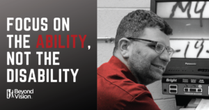 Black and white photo of David using a screen magnifying and wearing a bright red shirt. Text says "Focus on the ability, not the disability"