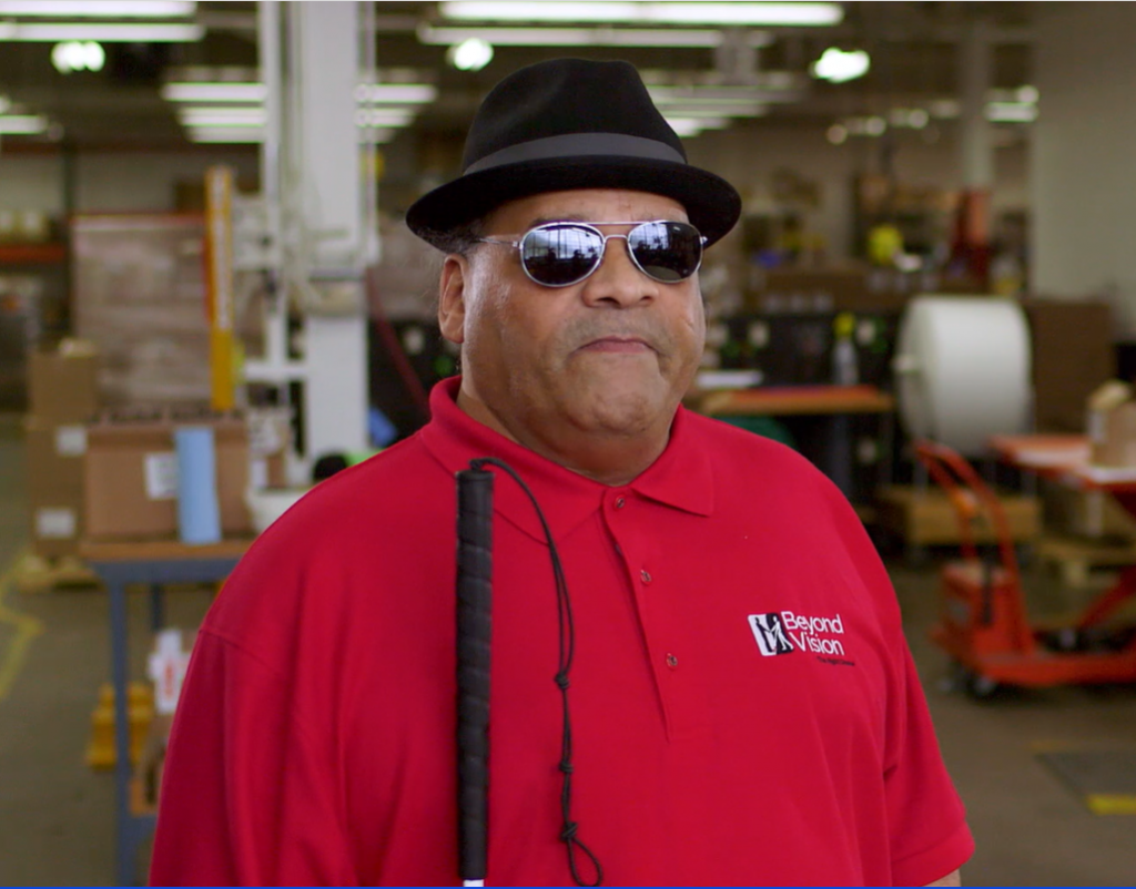 Photo of Julius wearing a bright red Beyond Vision polo shirt.
