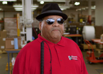 Photo of Julius wearing a bright red Beyond Vision polo shirt.