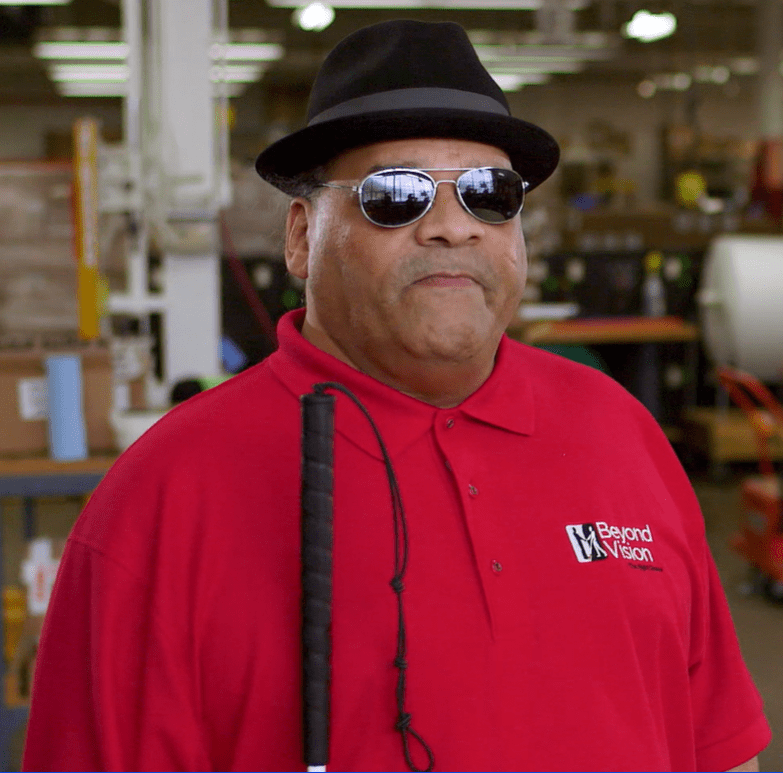 Photo of Julius wearing a bright red Beyond Vision polo shirt.