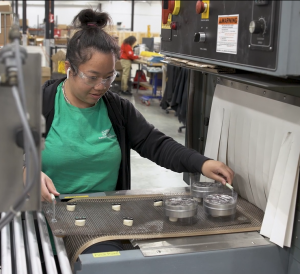 Beyond Vision employee placing products into the heat tunnel for shrink wrapping