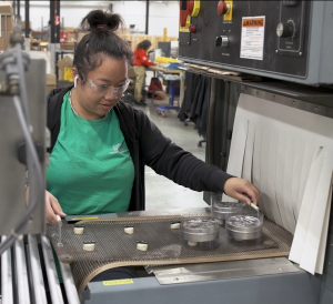 Assembly and packaging employee placing products into a heat tunnel for shrink wrapping