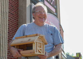 Photo of Rick standing outside Beyond Vision holding a wooden bird house