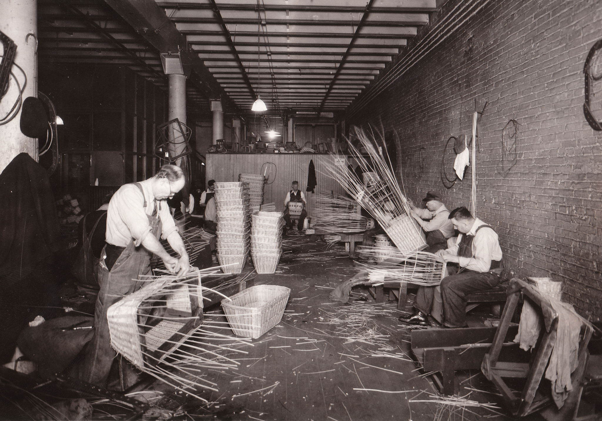 Greyscale photo of men weaving baskets by hand.