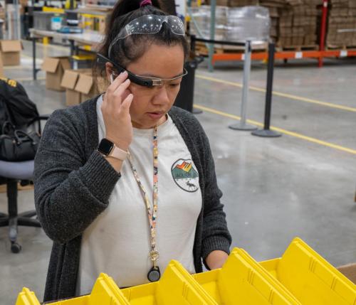 Photo of PangNhia using Envision glasses to help on the job in Assembly & Packaging at Beyond Vision.