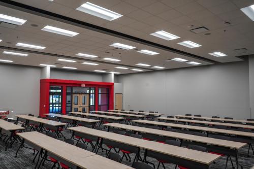 Mulit purpose room that features a cloud panel ceiling with rows of modern tables.