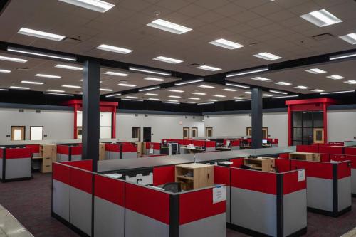 Open office area that features a cloud panel ceiling, modern cubicles, collaboration rooms and a casual seating area.   